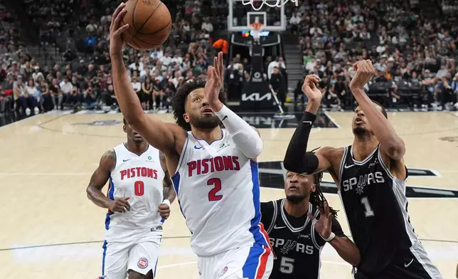 Detroit Pistons guard Cade Cunningham (2) drives to the basket against San Antonio Spurs forward Victor Wembanyama (1) and guard Stephon Castle (5) during the first half of an NBA basketball game in San Antonio, Thursday, March 5, 2026. (AP Photo/Eric Gay)
