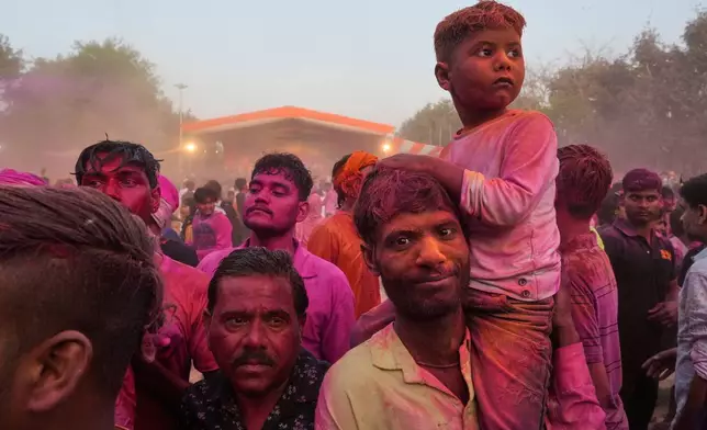 Devotees smeared with colors watch artists perform during Holi festival celebrations at the Shri Krishna Janmabhoomi Temple complex in Mathura, India, on Feb. 27, 2026. (AP Photo/Manish Swarup)