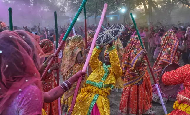 Women devotees symbolically beat men with wooden sticks to mark Lathmar Holi during Holi festival celebrations at the Shri Krishna Janmabhoomi Temple complex in Mathura, India, on Feb. 27, 2026. (AP Photo/Manish Swarup)