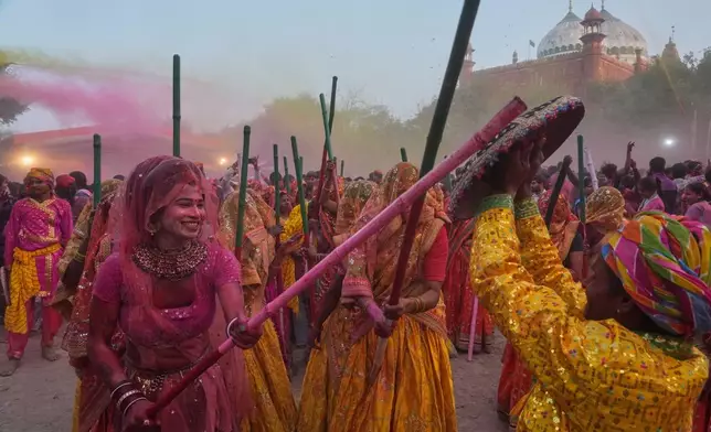 A member of transgender community with other women devotees symbolically beat men with wooden sticks to mark Lathmar Holi during Holi festival celebrations at the Shri Krishna Janmabhoomi Temple complex in Mathura, India, on Feb. 27, 2026. (AP Photo/Manish Swarup)