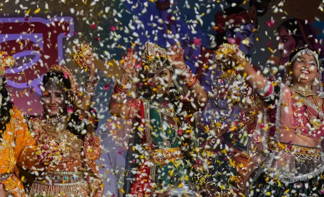 Artists dressed as the Hindu deities Lord Krishna and Radha throw flower petals during Holi festival celebrations at the Shri Krishna Janmabhoomi Temple complex in Mathura, India, on Feb. 27, 2026. (AP Photo/Manish Swarup)