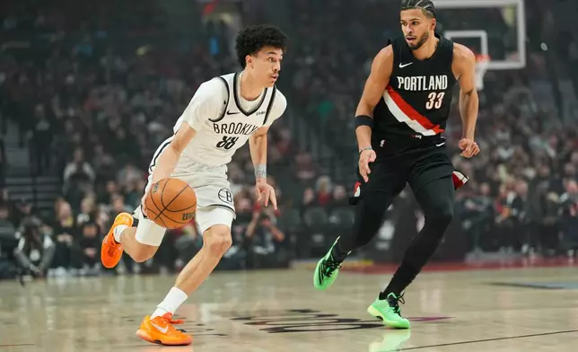 Brooklyn Nets guard Nolan Traore (88) tooks to get past Portland Trail Blazers forward Toumani Camara (33) during the first half of an NBA basketball game Monday, March 23, 2026, in Portland, Ore. (AP Photo/Jenny Kane)