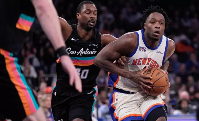 New York Knicks' Og Anunoby, right, drives to the basket past San Antonio Spurs' Harrison Barnes during the first half of an NBA basketball game Sunday, March 1, 2026, in New York. (AP Photo/Seth Wenig)