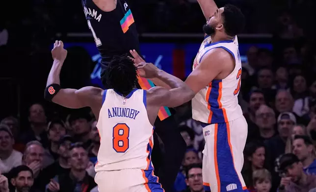 San Antonio Spurs' Victor Wembanyama, top, shoots over New York Knicks' Og Anunoby (8), left, and Karl-Anthony Towns during the first half of an NBA basketball game Sunday, March 1, 2026, in New York. (AP Photo/Seth Wenig)