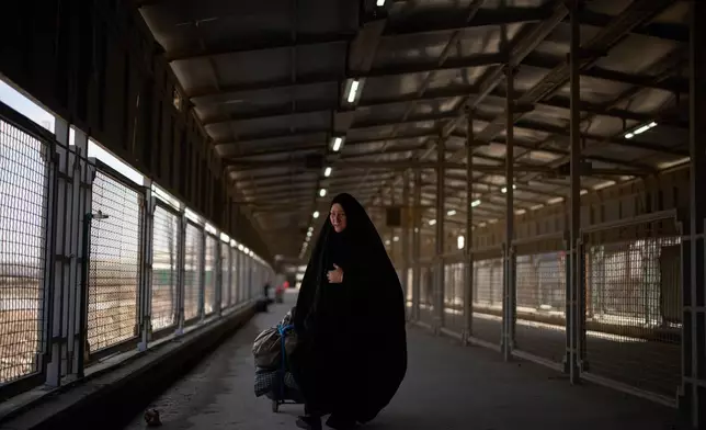 Carrying her belongings a woman crosses the Shalamcheh border crossing between Iran and Iraq, near Basra, Iraq, Sunday, March 29, 2026. (AP Photo/Leo Correa)