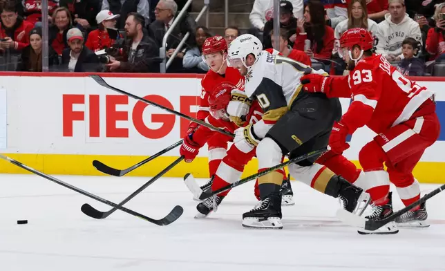 Vegas Golden Knights center Colton Sissons (10) is surrounded by , from left, Detroit Red Wings left wing Lucas Raymond (23), center Dylan Larkin, and right wing Alex DeBrincat (93) while chasing a loose puck during the second period of an NHL hockey game Wednesday, March 4, 2026, in Detroit. (AP Photo/Duane Burleson)