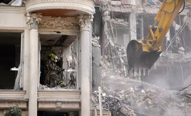 Rescue workers and first responders work at a residential building hit in an earlier U.S.-Israeli strike in Tehran, Iran, Monday, March 23, 2026. (AP Photo/Vahid Salemi)