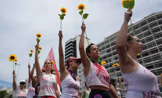 Women march marking International Women's Day on Copacabana beach, in Rio de Janeiro, Sunday, March 8, 2026. (AP Photo/Silvia Izquierdo)