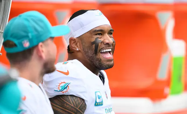 FILE - Miami Dolphins quarterback Tua Tagovailoa smiles on the bench during an NFL football game against the New Orleans Saints, Nov. 30, 2025, in Miami Gardens, Fla. (AP Photo/Doug Murray, File)