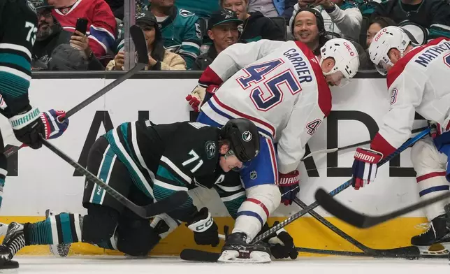 San Jose Sharks center Macklin Celebrini (71) reaches for the puck under Montréal Canadiens defenseman Alexandre Carrier (45) and defenseman Mike Matheson during the first period of an NHL hockey game in San Jose, Calif., Tuesday, March 3, 2026. (AP Photo/Jeff Chiu)