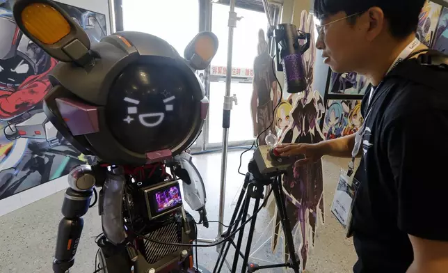 A man communicates with an ASUS Character Virtual Assistant, ROG Omni system during the AI EXPO in Taipei, Taiwan, Wednesday, March 25, 2026. (AP Photo/Chiang Ying-ying)