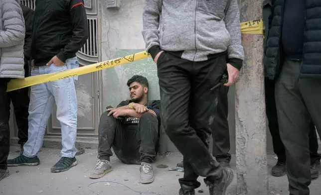 A volunteer sits on the floor as first responders inspect the rubble and search for victims at a residential building hit in an overnight strike during the U.S.-Israeli military campaign in Tabriz, East Azerbaijan Province, northwestern Iran, Tuesday, March 24, 2026. (AP Photo/Matin Hashemi)