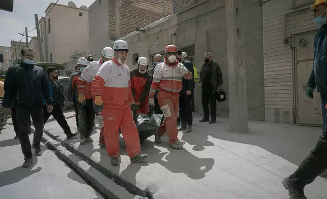 First responders carry a body from the site of a residential building hit in an overnight strike during the U.S.-Israeli military campaign in Tabriz, East Azerbaijan Province, northwestern Iran, Tuesday, March 24, 2026. (AP Photo/Matin Hashemi)