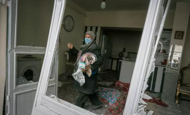 A woman collects belongings from a house damaged when a nearby residential building was hit in an overnight strike during the U.S.-Israeli military campaign in Tabriz, East Azerbaijan Province, northwestern Iran, Tuesday, March 24, 2026. (AP Photo/Matin Hashemi)