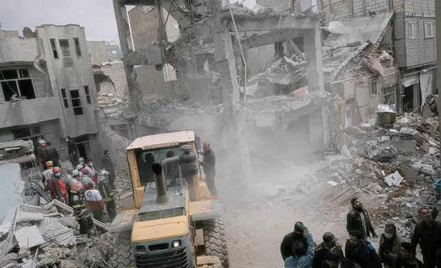 First responders use an excavator to clean the debris and search for victims at a residential building hit in an overnight strike during the U.S.-Israeli military campaign in Tabriz, East Azerbaijan Province, northwestern Iran, Tuesday, March 24, 2026. (AP Photo/Matin Hashemi)