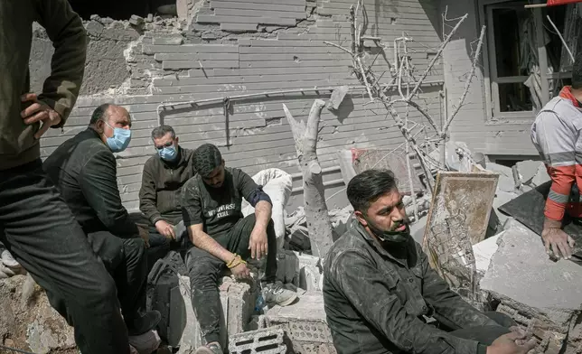 Volunteers rest as first responders inspect the rubble and search for victims at a residential building hit in an overnight strike during the U.S.-Israeli military campaign in Tabriz, East Azerbaijan Province, northwestern Iran, Tuesday, March 24, 2026. (AP Photo/Matin Hashemi)