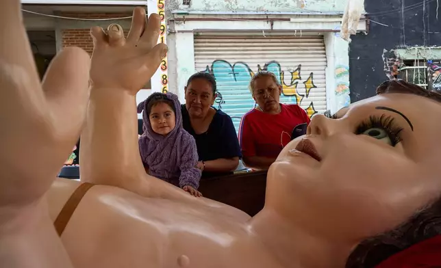 Parishioners take part in an offering to a giant Baby Jesus in Mexico City, Tuesday, March 10, 2026. (AP Photo/Ginnette Riquelme)