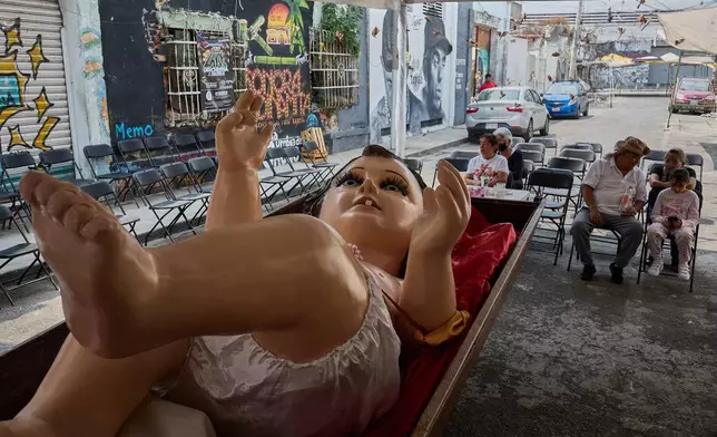 Parishioners take part in an offering to a giant Baby Jesus in Mexico City, Tuesday, March 10, 2026. (AP Photo/Ginnette Riquelme)