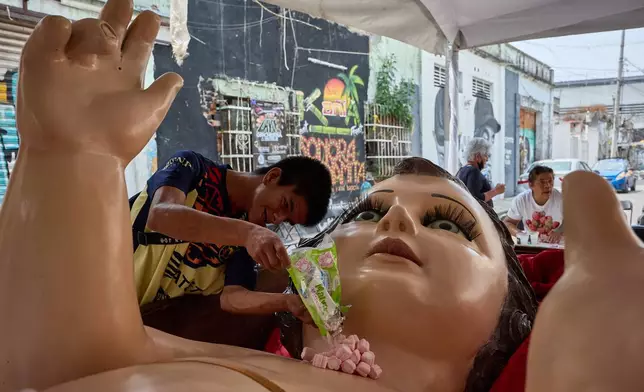 A parishioner offers candy to a giant Baby Jesus in Mexico City, Tuesday, March 10, 2026. (AP Photo/Ginnette Riquelme)