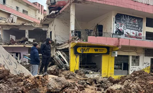 People check the damage left by Israeli airstrikes, Saturday, March 7, 2026 in the village of Nabi Chit, eastern Lebanon late Friday, where Israeli forces landed overnight and dug a grave in a cemetery searching for Israeli co-pilot Ron Arad who was captured and then went missing after his fighter jet crashed over south Lebanon in 1986. (AP Photo/Ali Salem)