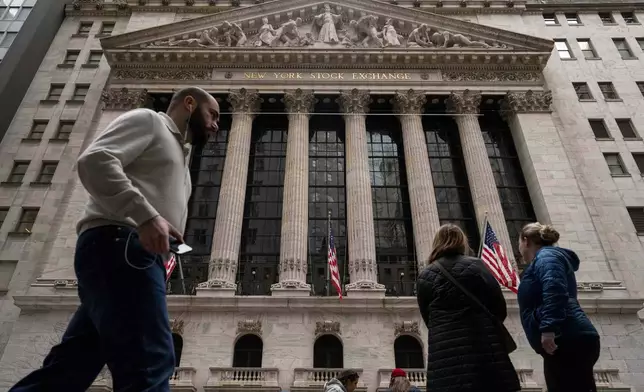 People walk past the New York Stock Exchange, Friday, March 27, 2026, in New York. (AP Photo/Yuki Iwamura)