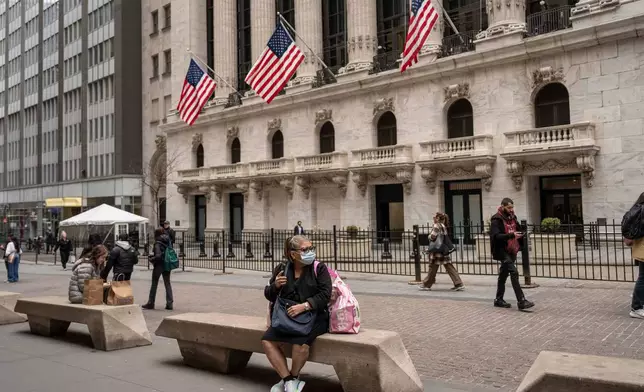 People sit on benches outside the New York Stock Exchange, Friday, March 27, 2026, in New York. (AP Photo/Yuki Iwamura)