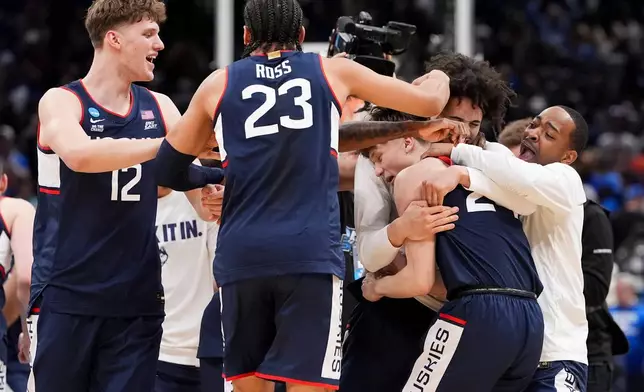 UConn guard Braylon Mullins, right, celebrates his game winning basketball with teammates after the second half in the Elite Eight of the NCAA college basketball tournament, Sunday, March 29, 2026, in Washington. (AP Photo/Stephanie Scarbrough)