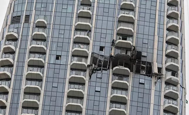 Workers inspect damage caused by a drone strike overnight at the Address Creek Harbour hotel in Dubai, United Arab Emirates, March 12, 2026. (AP Photo/Fatima Shbair)