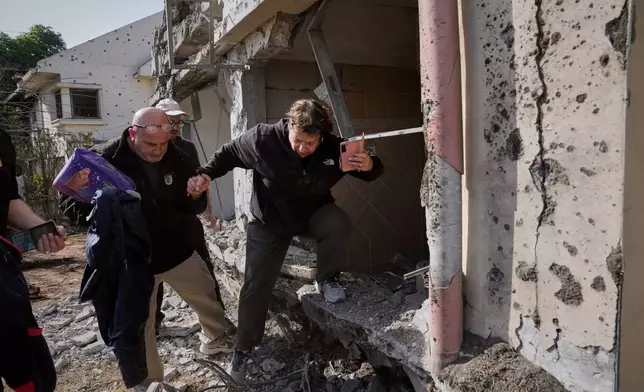 A woman gathers belongings from her family's home after it was damaged by a projectile launched from Lebanon, in Haniel, central Israel, Thursday, March 12, 2026. (AP Photo/Baz Ratner)