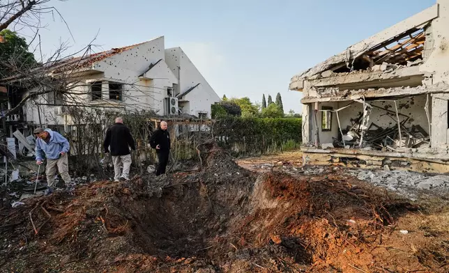 People inspect homes damaged by a projectile launched from Lebanon, in Haniel central Israel, Thursday, March 12, 2026. (AP Photo/Baz Ratner)