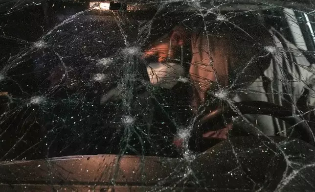 A man inspects a car damaged in an Israeli airstrike at the Ramlet al-Baida public beach in Beirut, Lebanon, early Thursday, March 12, 2026. (AP Photo/Bilal Hussein)