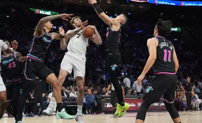 San Antonio Spurs center Luke Kornet (7) fights for control of the ball against Miami Heat center Kel'el Ware, left, and guard Tyler Herro, second from right, during the first half of an NBA basketball game, Monday, March 23, 2026, in Miami. (AP Photo/Lynne Sladky)