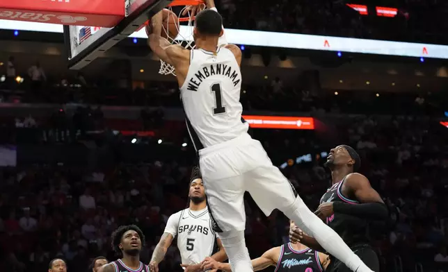 San Antonio Spurs forward Victor Wembanyama (1) dunks over Miami Heat center Bam Adebayo, right, during the first half of an NBA basketball game, Monday, March 23, 2026, in Miami. (AP Photo/Lynne Sladky)
