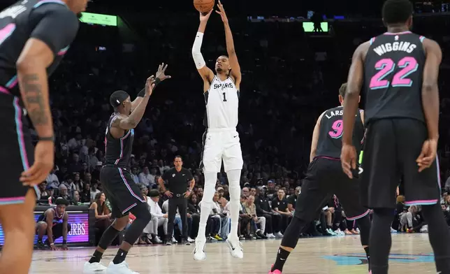 San Antonio Spurs forward Victor Wembanyama (1) shoots a three-point basket over Miami Heat center Bam Adebayo (13) during the first half of an NBA basketball game, Monday, March 23, 2026, in Miami. (AP Photo/Lynne Sladky)
