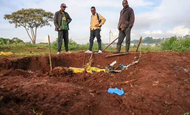 People gather at the scene of a mass grave where 33 bodies were exhumed at a cemetery in Kericho, Western Kenya Thursday, March 26, 2026. (AP Photo/Andrew Kasuku)