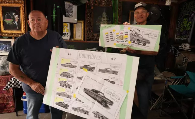 Freehand pinstriping artist Danny Alvarado, left, with his assistant Clarence Spears, looks at sketches used for the new United States Postal Service lowriders stamps at his workshop in Monrovia, Calif., Tuesday, March 10, 2026. (AP Photo/Damian Dovarganes)