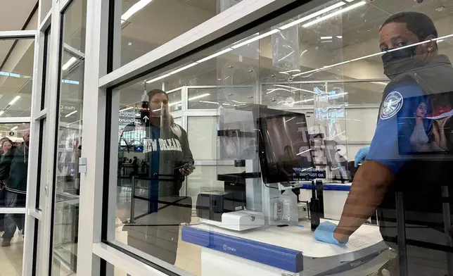 A Transportation Security Administration agent checks a passenger's identification at Hartsfield-Jackson International Airport on Saturday, March 21, 2026. (AP Photo/Jeff Amy)