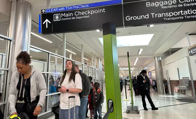 Passengers wait outside a Transportation Security Administration checkpoint at Hartsfield-Jackson Atlanta International Airport on Saturday, March, 21, 2026, (AP Photo/Jeff Amy)