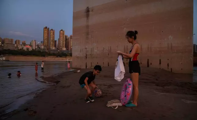 FILE - People prepare to swim in the Yangtze River near a bridge support column that shows previous water levels in southwestern China's Chongqing Municipality, Aug. 19, 2022. (AP Photo/Mark Schiefelbein, File)