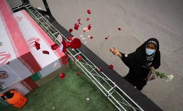A woman throws rose petals on the coffins during funeral of mostly children killed in what Iranian officials said was an Israeli-U.S. strike Feb. 28 on a girls' elementary school in Minab, Iran, Tuesday, March 3, 2026. (Amirhossein Khorgooei/ISNA via AP)