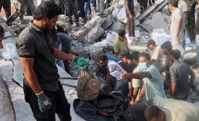 A man hold a children's backpack as rescue workers and residents search through the rubble in the aftermath of an Israeli-U.S. strike on a girls' elementary school in Minab, Iran, Saturday, Feb. 28, 2026. (Abbas Zakeri/Mehr News Agency via AP)