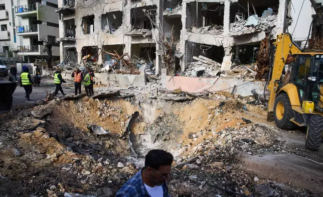 Rescue workers and military personnel survey the scene of a direct hit a day after an Iranian missile struck in Tel Aviv, Israel, Sunday, March 1, 2026. (AP Photo/Oded Balilty)