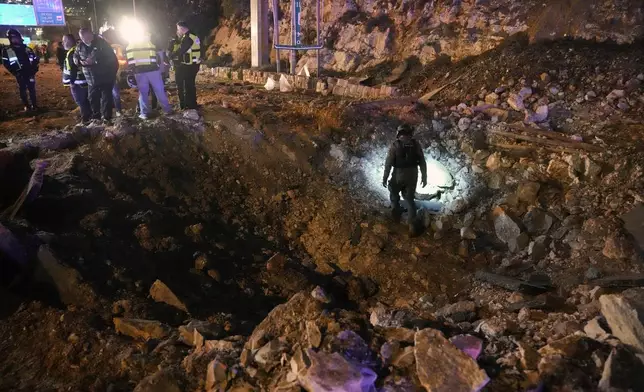 Israeli security forces inspect a damaged road after a missile launched from Iran struck Jerusalem, Sunday, March 1, 2026.(AP Photo/Mahmoud Illean)