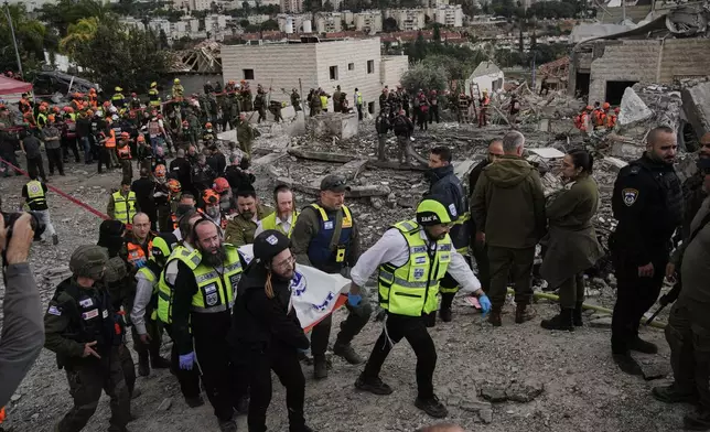 Rescue workers and military personnel carry a body of a victim from the scene where several people were killed by an Iranian missile strike in Beit Shemesh, Israel Sunday, March 1, 2026. (AP Photo/Leo Correa)
