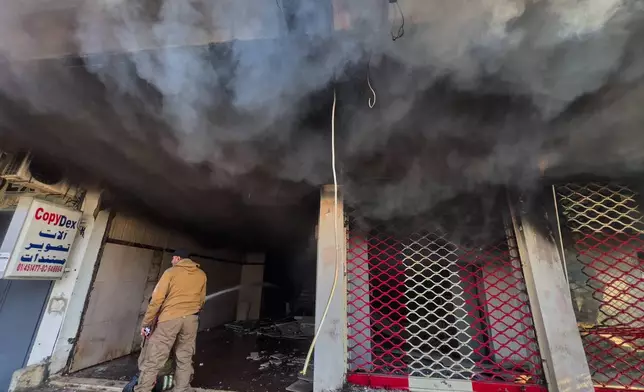 A firefighter extinguishes fire at a building that was hit by an Israeli airstrike in Dahiyeh, a southern suburb of Beirut, Lebanon, Tuesday, March 3, 2026. (AP Photo/Hussein Malla)