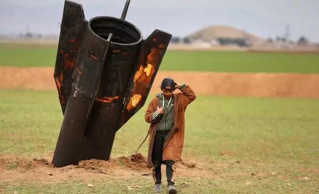 A shepherd boy walks away from an unexploded Iranian projectile that landed in an open field in the outskirts of Qamishli, eastern Syria, Wednesday, March 4, 2026.(AP Photo/Baderkhan Ahmad)