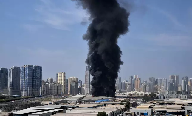 A black plume of smoke rises from a warehouse at the industrial area of Sharjah City in the United Arab Emirates following reports of Iranian strikes in Dubai, United Arab Emirates, Sunday, March 1, 2026. (AP Photo/Altaf Qadri)