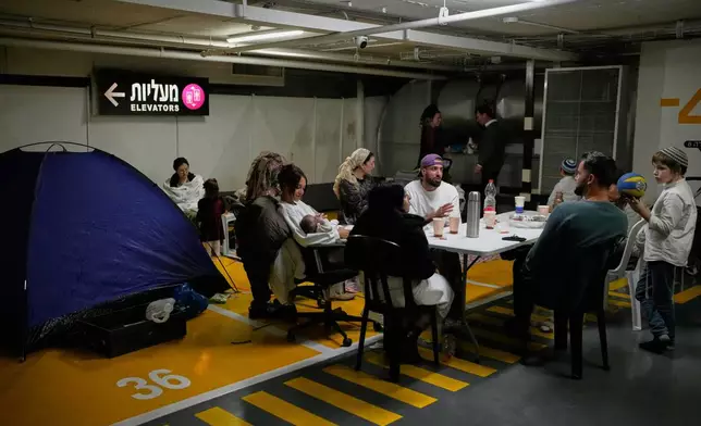 People take shelter in an underground parking garage as air raid sirens warn of incoming missiles strike by Iran, in Tel Aviv, Israel, Saturday, Feb. 28, 2026. (AP Photo/Ohad Zwigenberg)