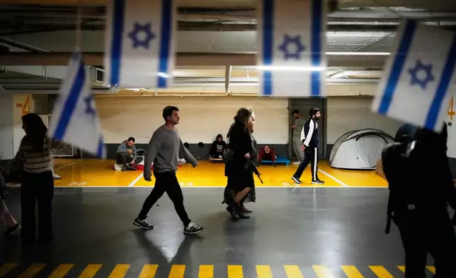 People take shelter in an underground parking garage as air raid sirens warn of incoming missiles strike by Iran, in Tel Aviv, Israel, Saturday, Feb. 28, 2026. (AP Photo/Ohad Zwigenberg)