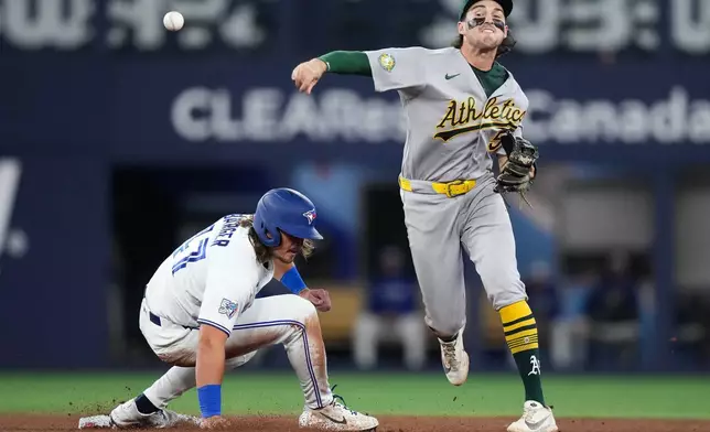 Athletics shortstop Jacob Wilson (5) forces out Toronto Blue Jays outfielder Addison Barger (47) at second base them turns the double play over to first to out Toronto Blue Jays third baseman Kazuma Okamoto during fifth inning American League baseball action in Toronto on Sunday, March 29, 2026. (Nathan Denette/The Canadian Press via AP)